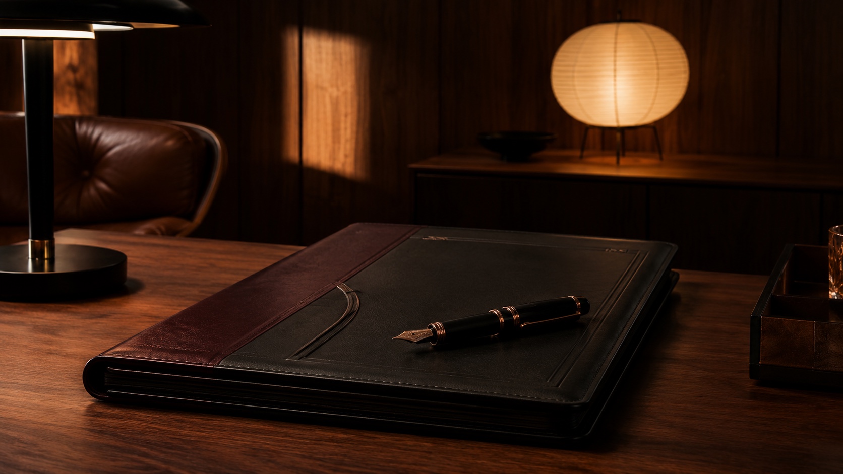 A leather-bound founding document and a Montblanc pen on a walnut desk, written once, held to